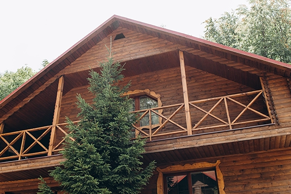 Fasada drewnianego domu z balkonem z barierka o krzyżowej konstrukcji.